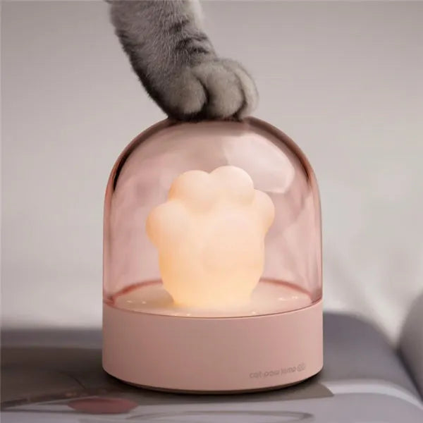 Grey and pink cat paw shaped USB rechargeable night light with adjustable brightness on a desk.
