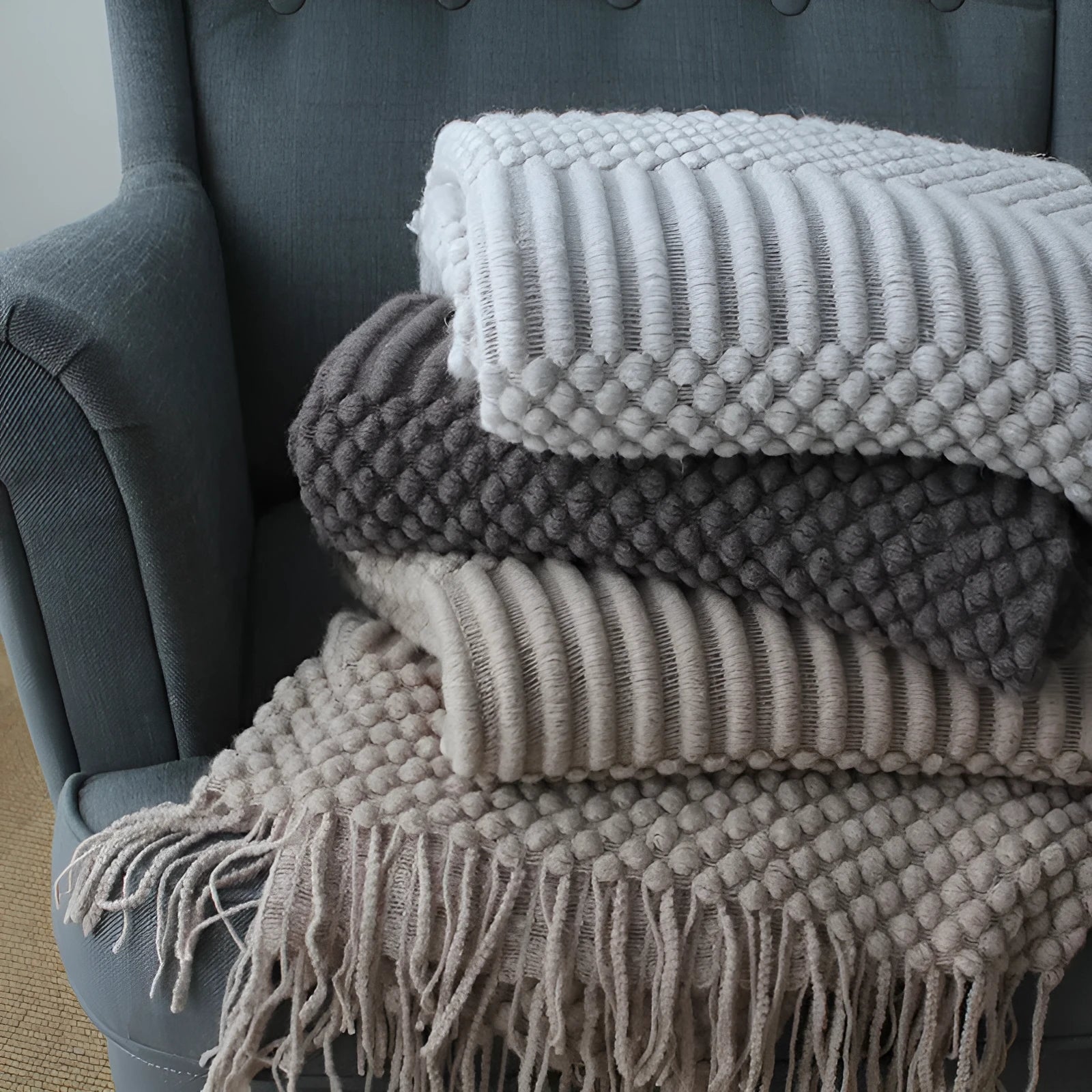Small grey polyester nap blanket measuring 127 by 170 centimetres folded on sofa