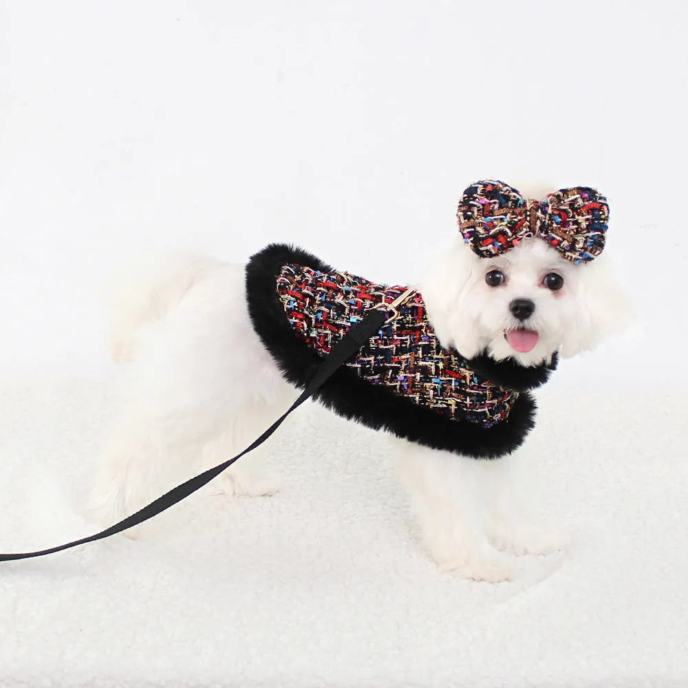 A dog wearing a classic cloth cloak chest harness with an attached hand holding rope.