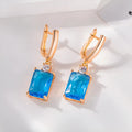 A pair of square-shaped gold and silver electroplated copper earrings showing front view.