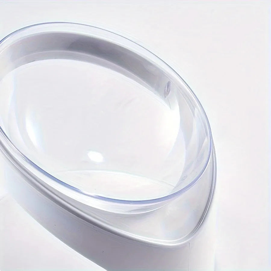 White clear plastic tilted cat food bowl on a flat surface.
