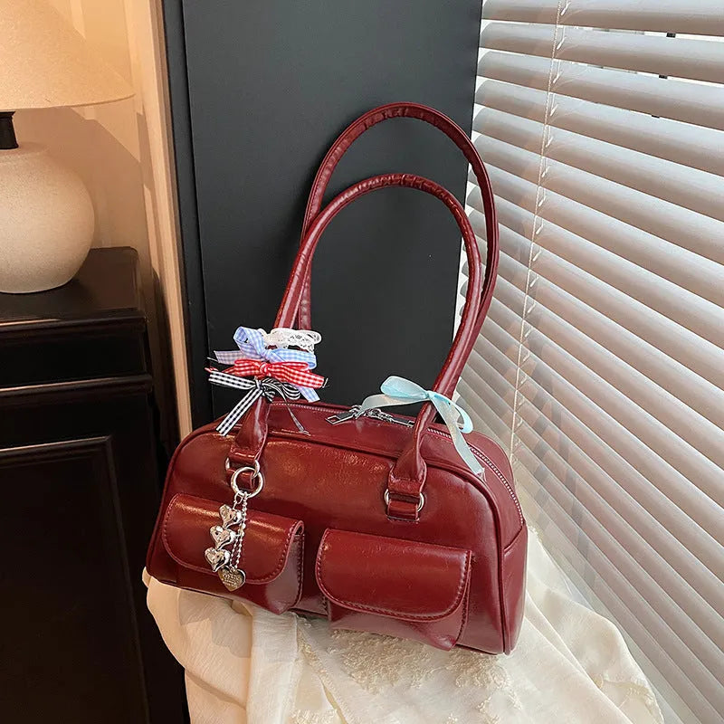 Brown PU leather women's pillow flap bag with double straps and a decorative ribbon pendant.