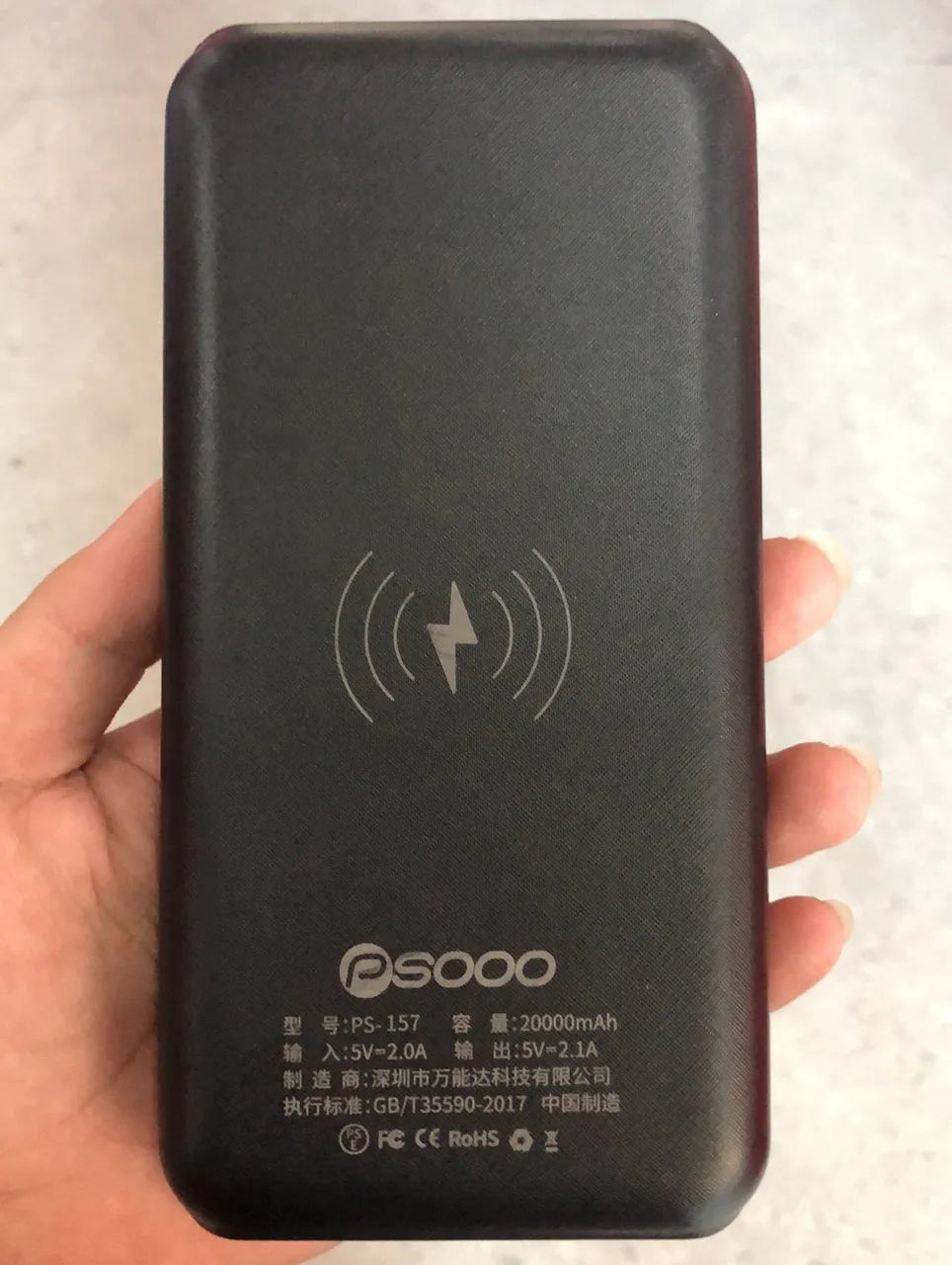 Black portable power bank with Qi wireless charging pad and three USB ports on the side
