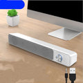Small black computer speaker with USB cable on desktop