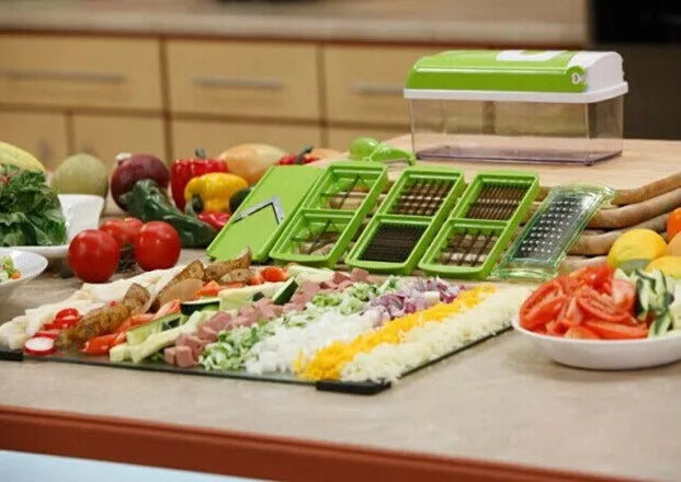 Green manual food chopper with multiple stainless steel accessories on a kitchen counter.