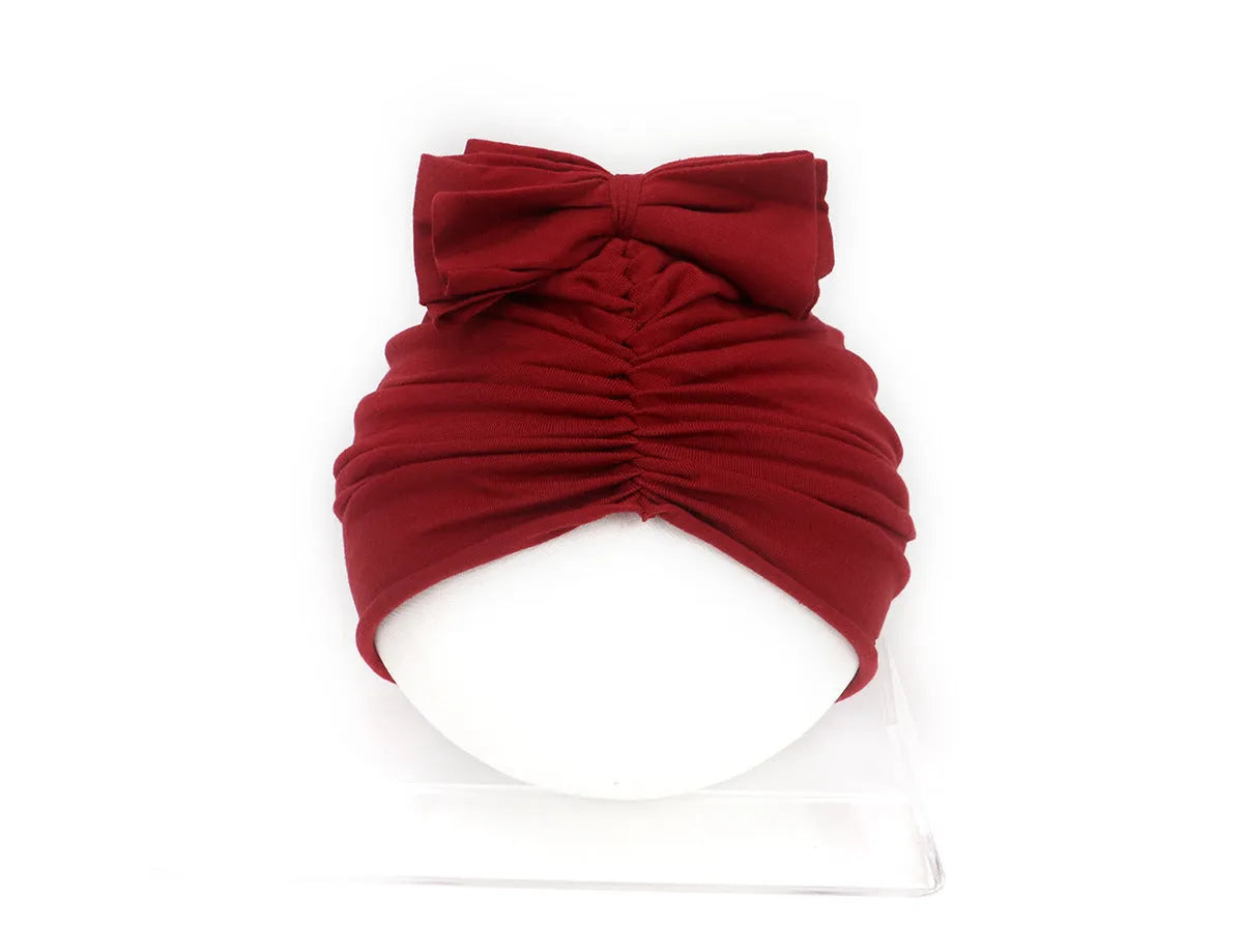 Soft knitted baby bonnet for newborns and toddlers in a solid colour on a mannequin head