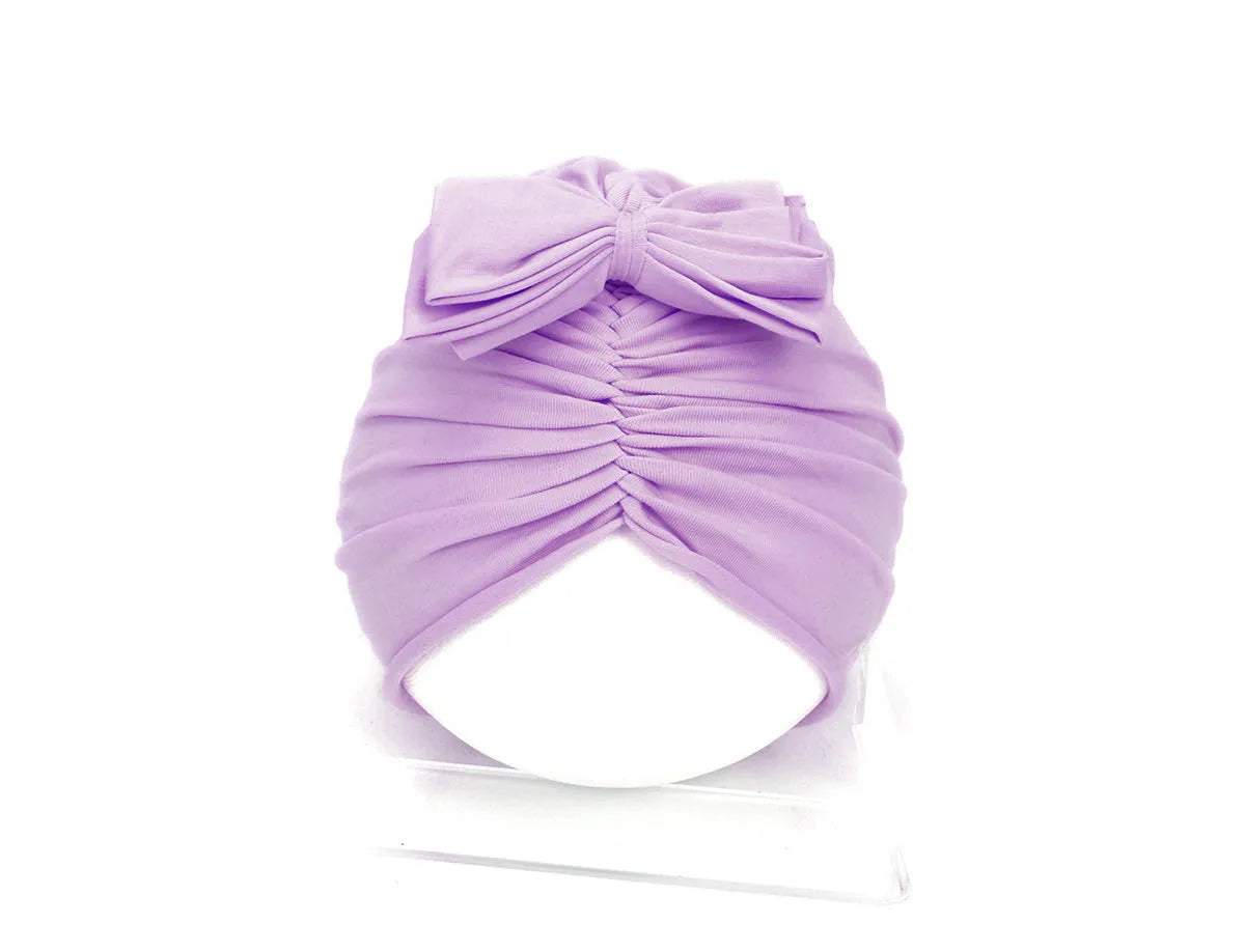 Soft knitted baby bonnet for newborns and toddlers in a solid colour on a mannequin head