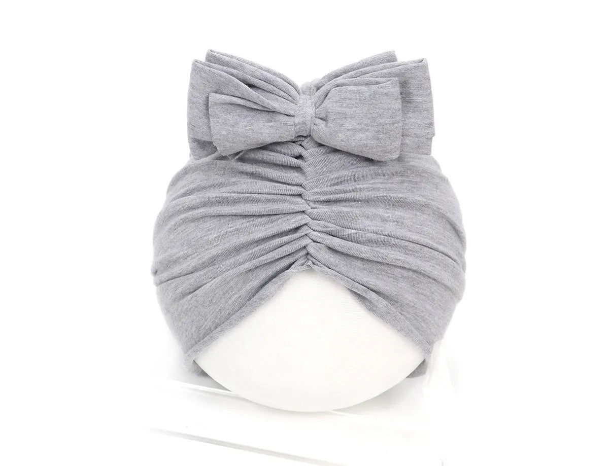 Soft knitted baby bonnet for newborns and toddlers in a solid colour on a mannequin head