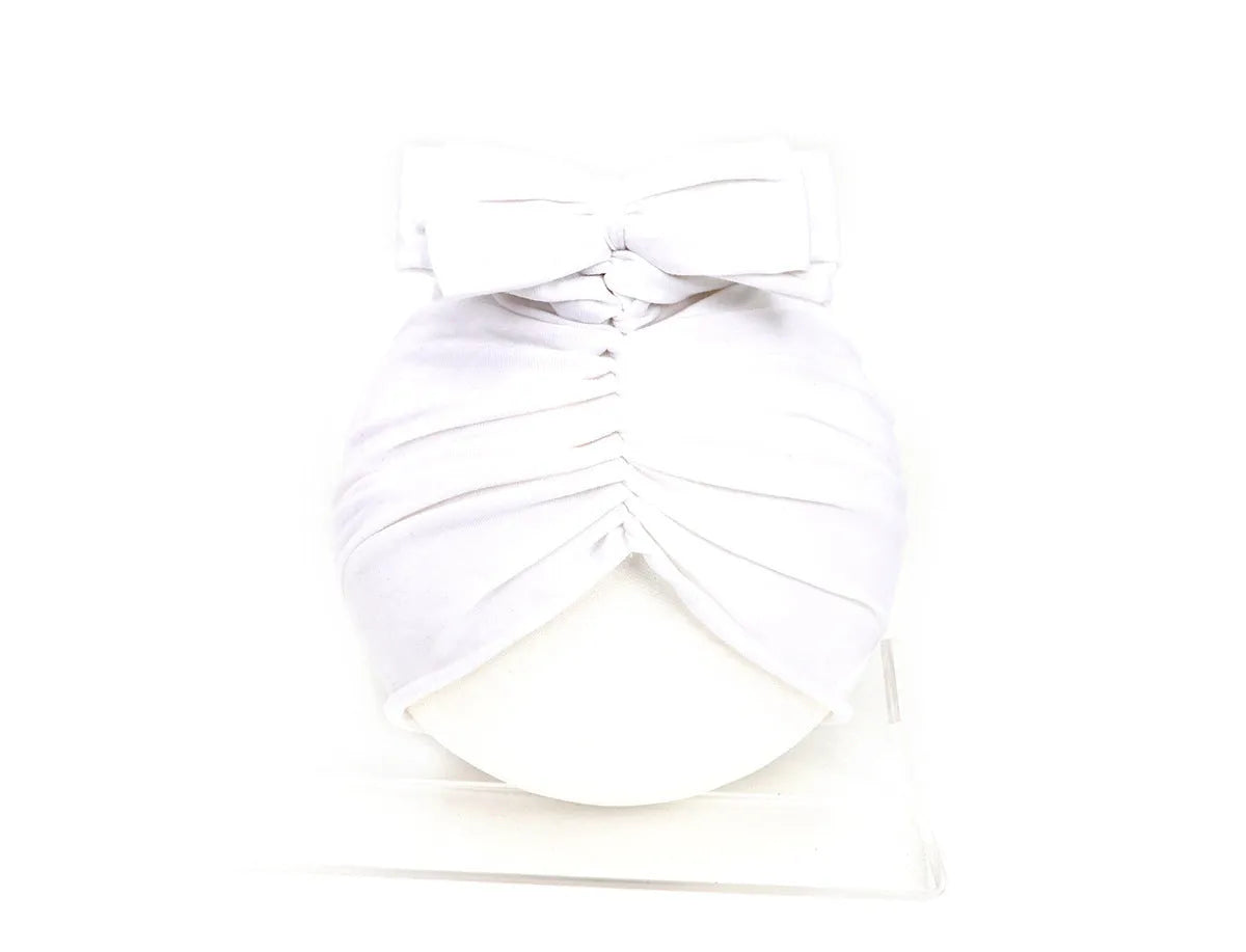 Soft knitted baby bonnet for newborns and toddlers in a solid colour on a mannequin head
