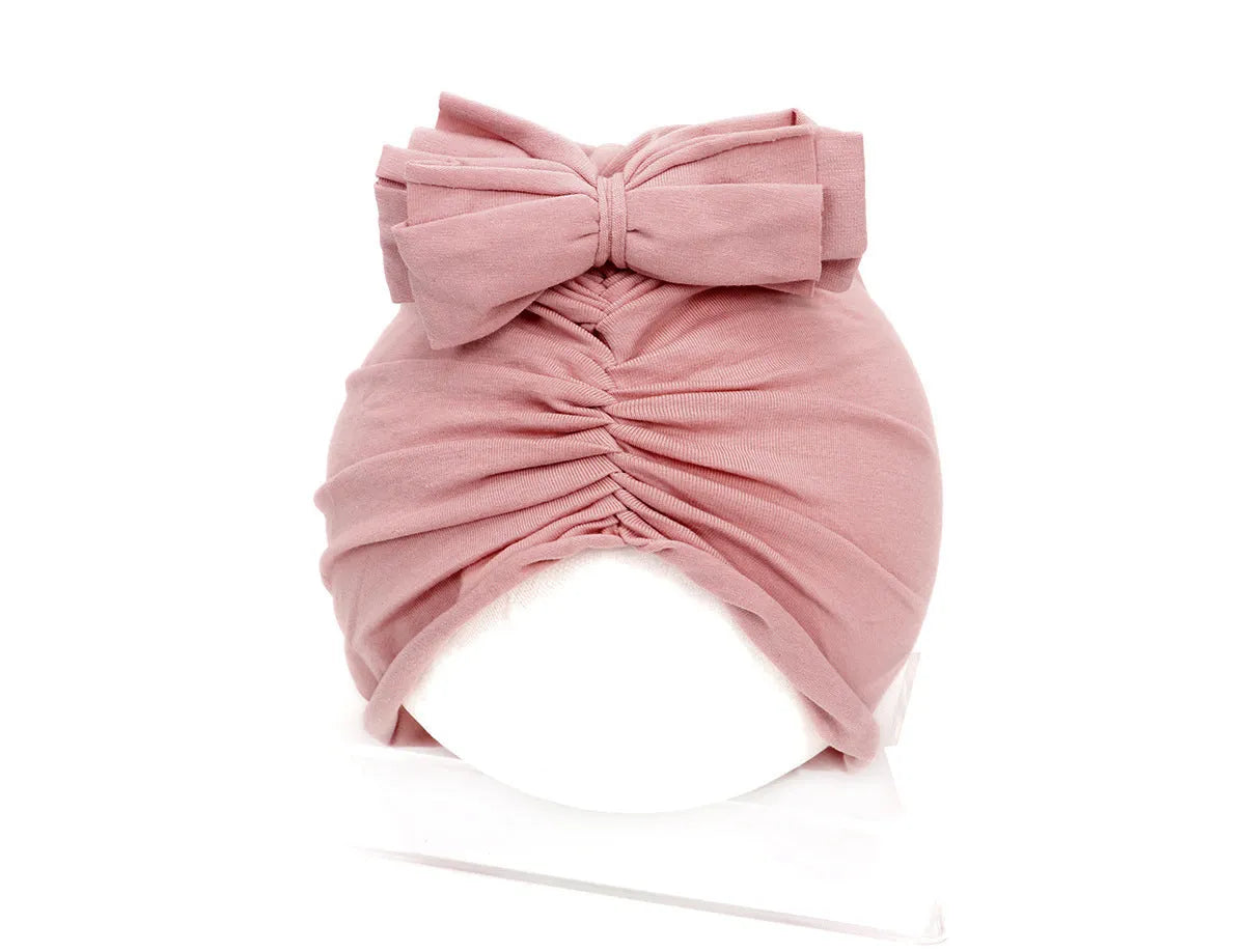 Soft knitted baby bonnet for newborns and toddlers in a solid colour on a mannequin head