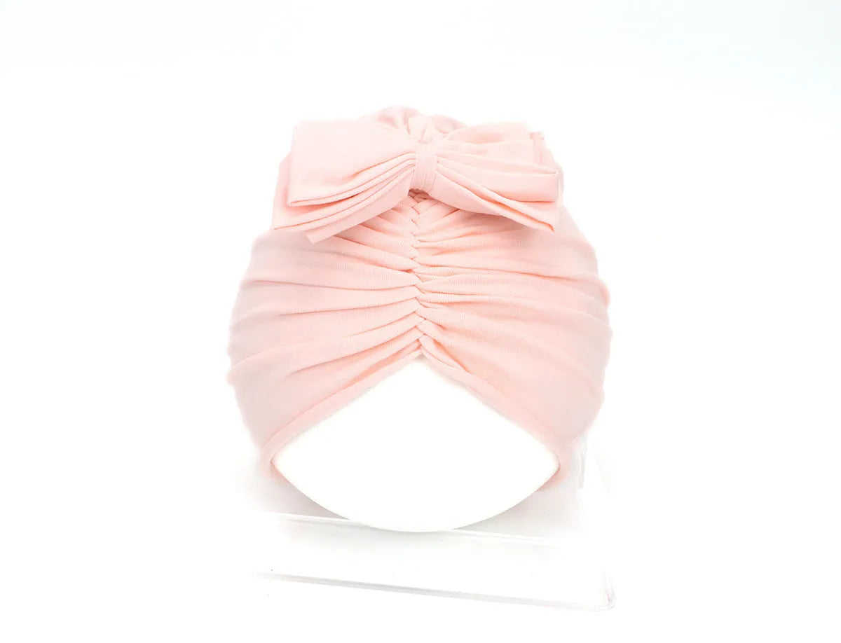 Soft knitted baby bonnet for newborns and toddlers in a solid colour on a mannequin head