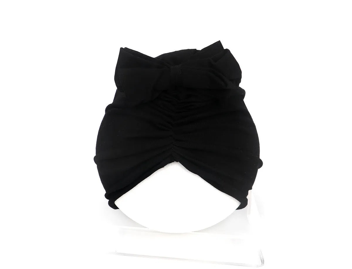 Soft knitted baby bonnet for newborns and toddlers in a solid colour on a mannequin head