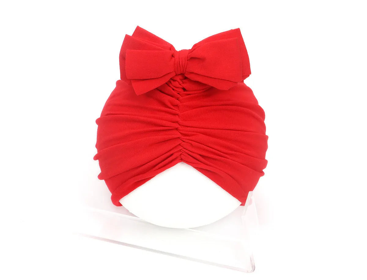 Soft knitted baby bonnet for newborns and toddlers in a solid colour on a mannequin head