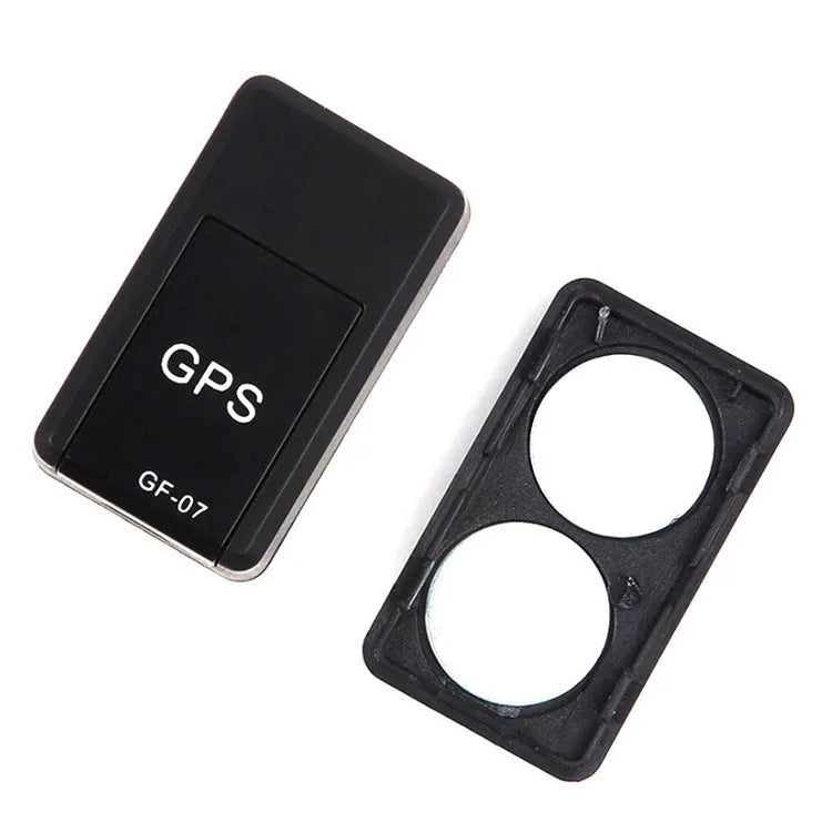 Black mini magnetic GPS tracker next to USB charging cable on a dark surface.