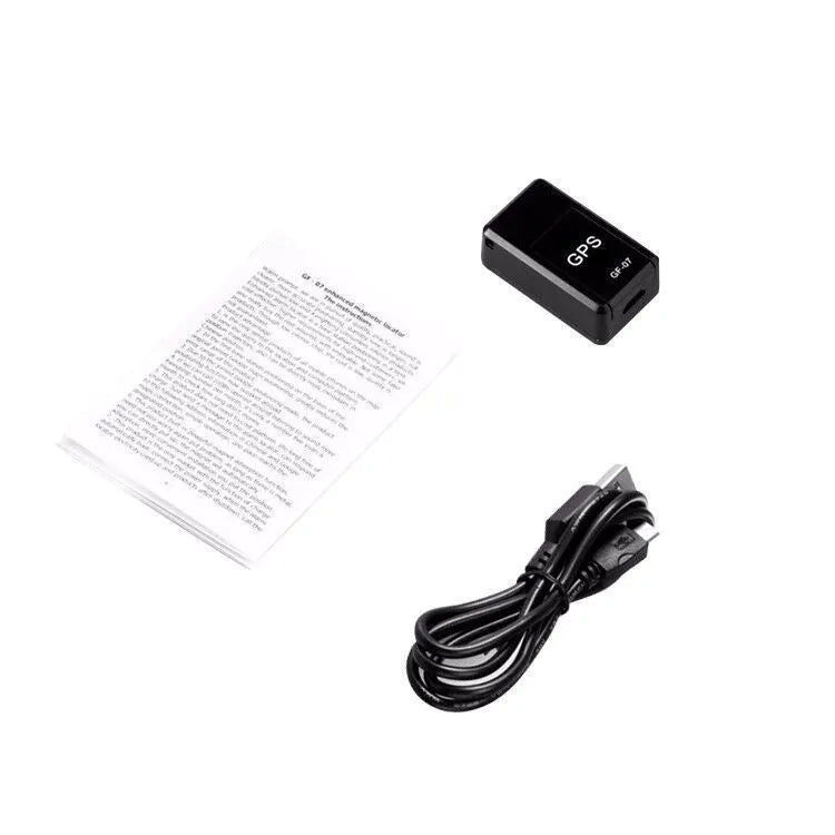 Black mini magnetic GPS tracker next to USB charging cable on a dark surface.