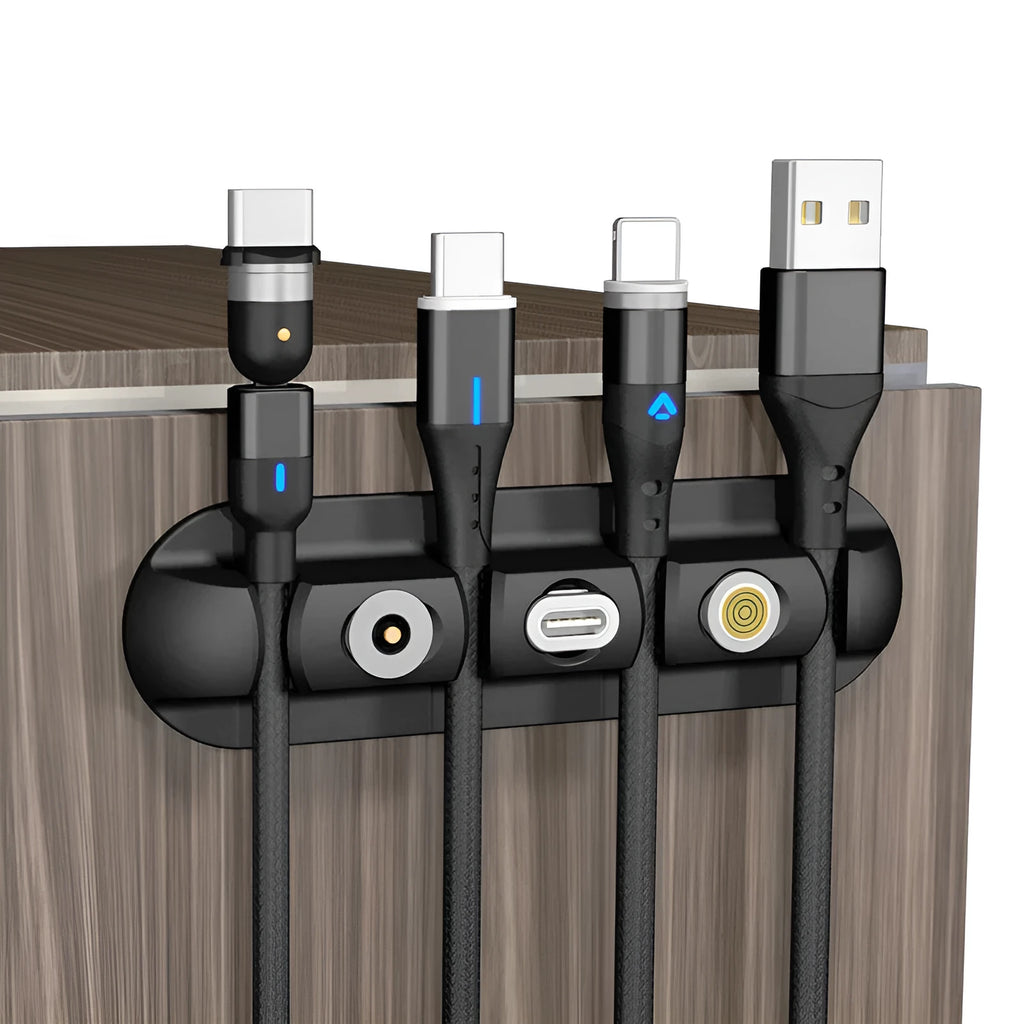 Black desktop magnetic cable organiser with soft plastic base on a desk.