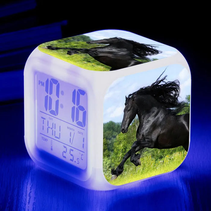 Square cartoon digital alarm clock with colour changing LED display on a plastic and plexiglass body.
