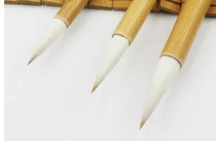Three traditional Chinese calligraphy brushes with wool hair tips and bamboo handles in large, medium, and small sizes