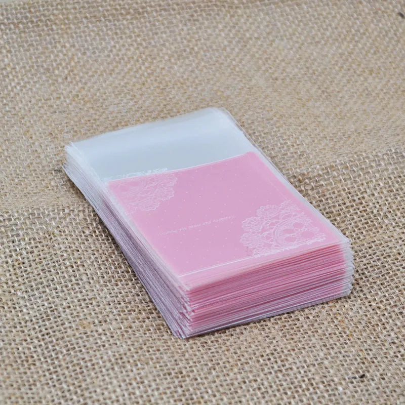 Pink self-adhesive plastic packaging bag with a 3cm flap, shown in a pack of 100.