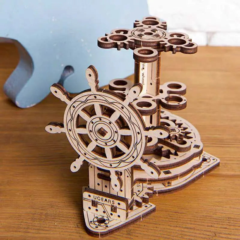 Assembled wooden steering wheel model functioning as a rotating pen holder on a desk.