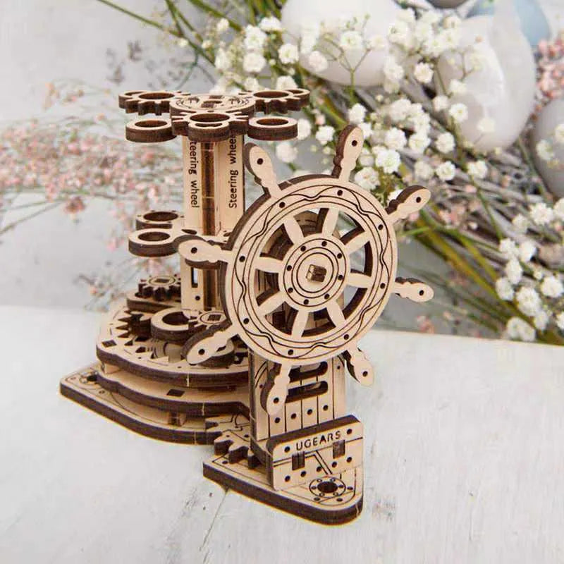 Assembled wooden steering wheel model functioning as a rotating pen holder on a desk.