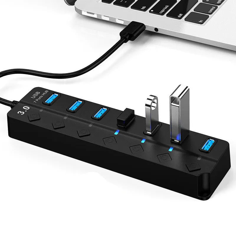 Black 7-port USB 3.0 hub with external power adapter on a desk.