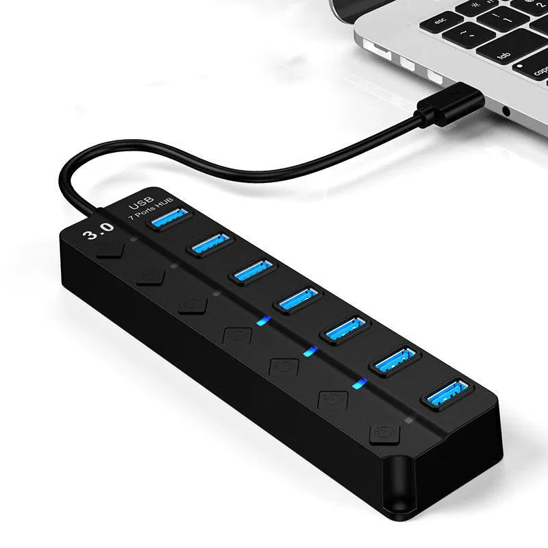 Black 7-port USB 3.0 hub with external power adapter on a desk.