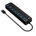 Black 7-port USB 3.0 hub with external power adapter on a desk.