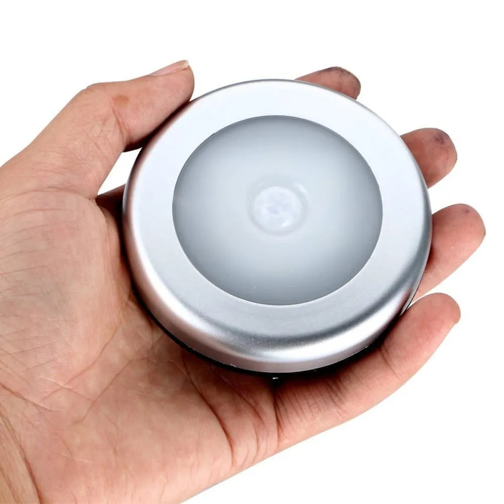 Silver circular wireless motion sensor night light on a table showing its 80mm diameter.