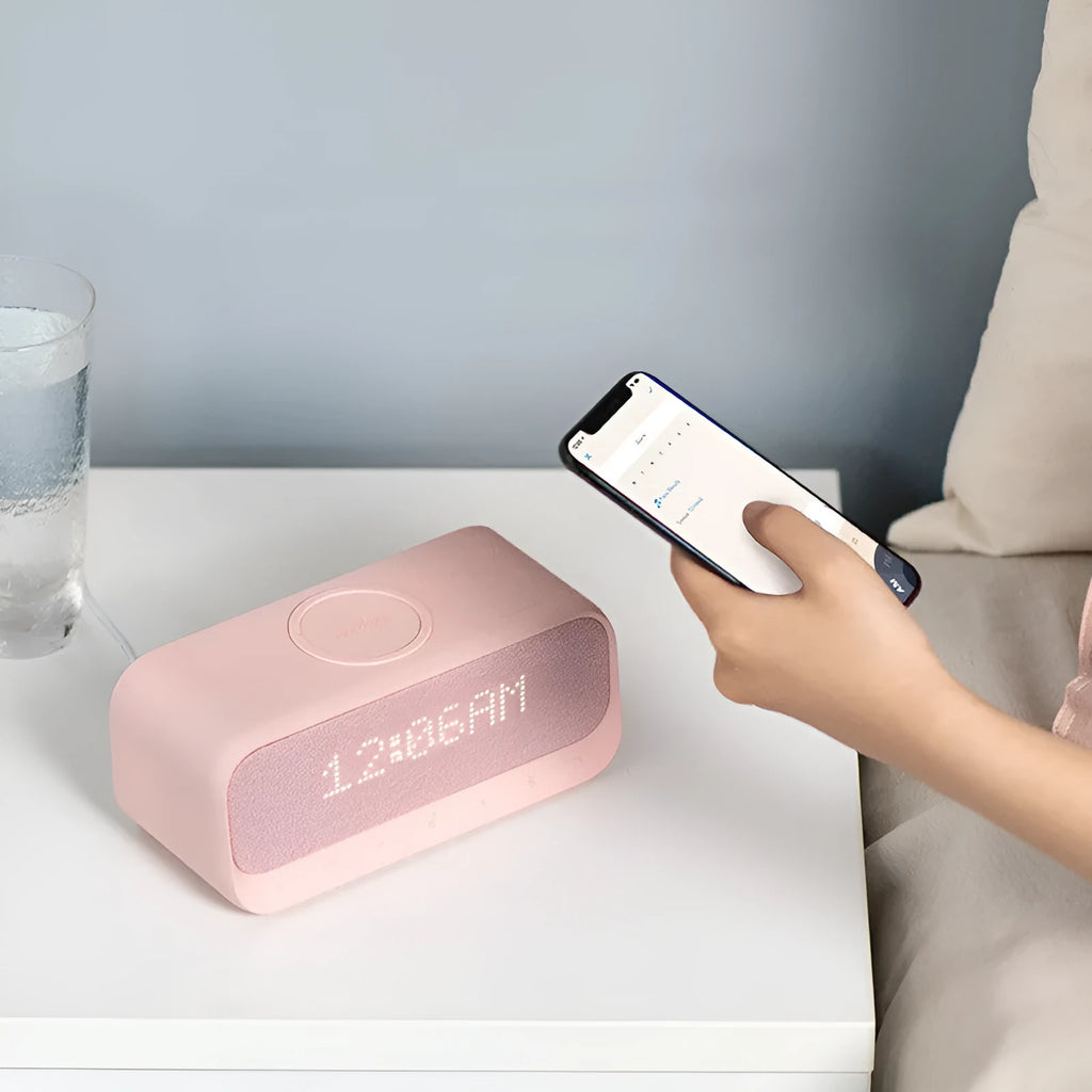 White or pink Anker Soundcore Bluetooth speaker with wireless charging pad and digital clock display