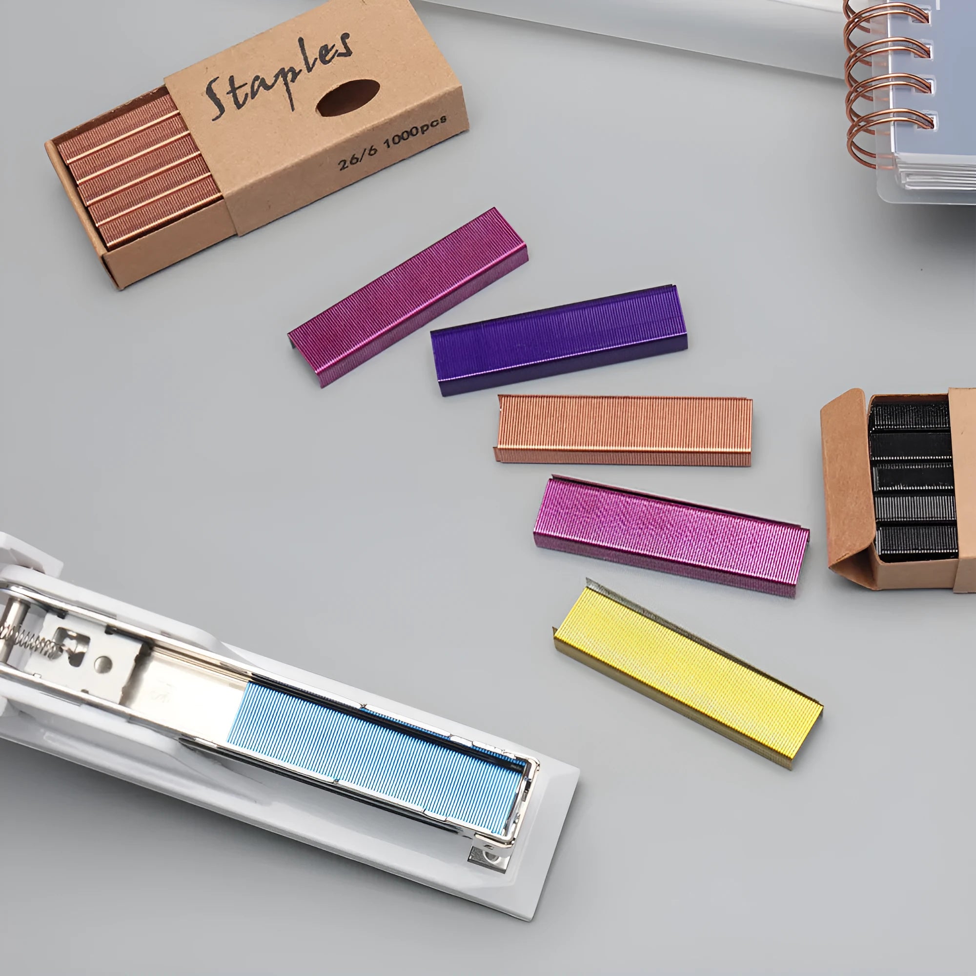 Box of 1000 metal office staples in rose gold, black, purple, and rose red finishes