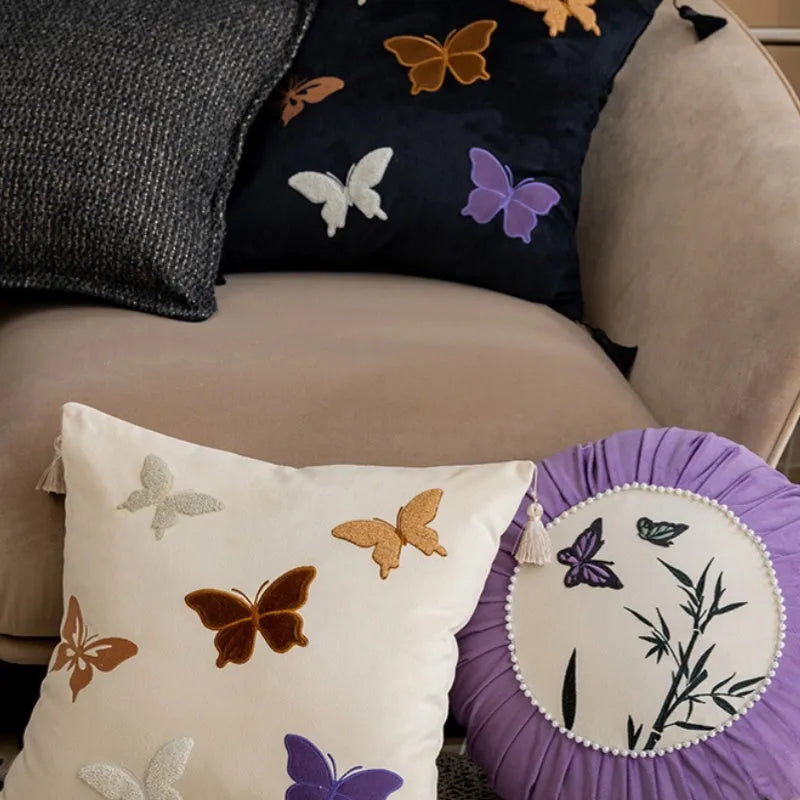 Square beige couch pillow with detailed Chinese-style butterfly embroidery.