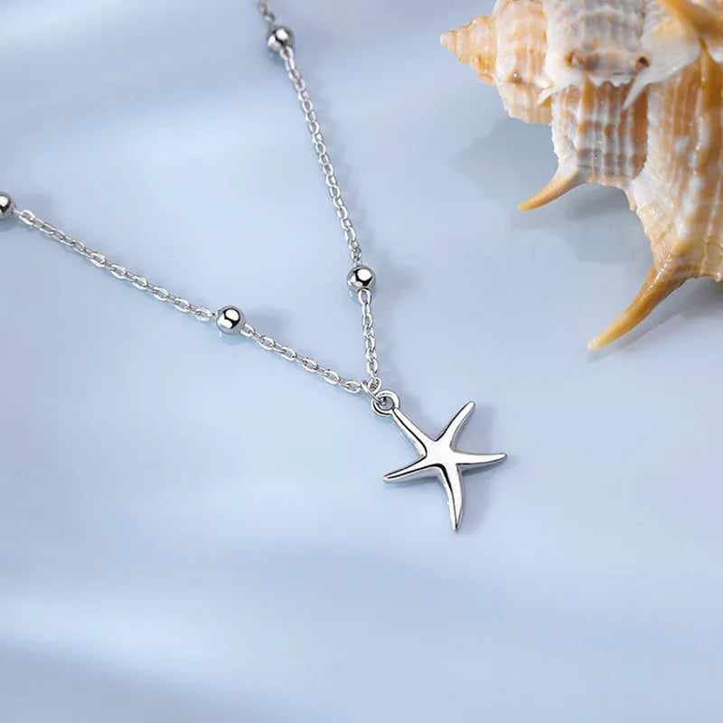 Close-up of a sterling silver anklet with a starfish charm on a round beaded chain.