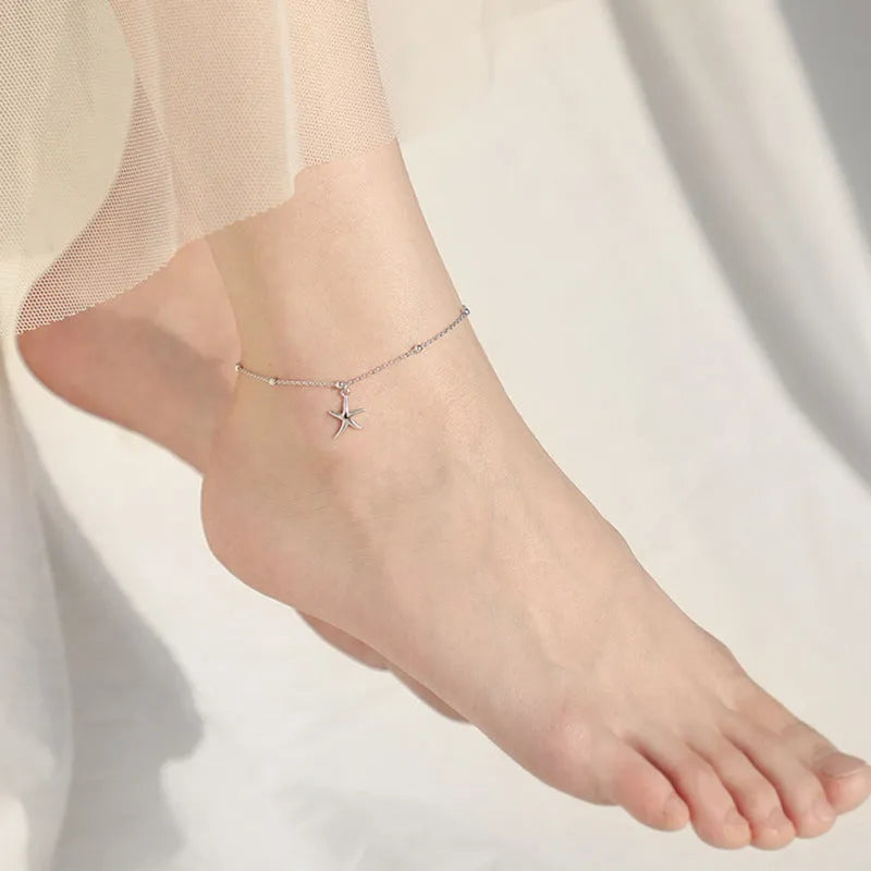 Close-up of a sterling silver anklet with a starfish charm on a round beaded chain.