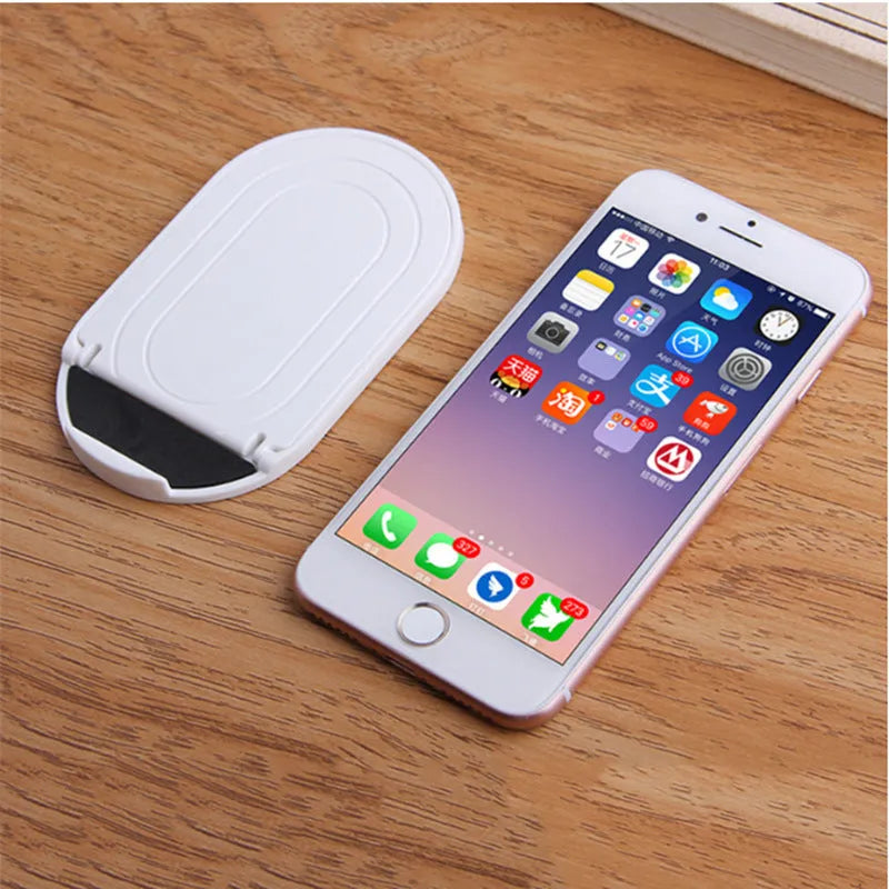 Plastic mobile phone stand with lazy bracket, holding a smartphone, shown in multiple colour options.
