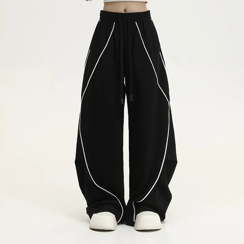 Black pleated wide-leg trousers with stripe pattern showing loose fit and mid waist design