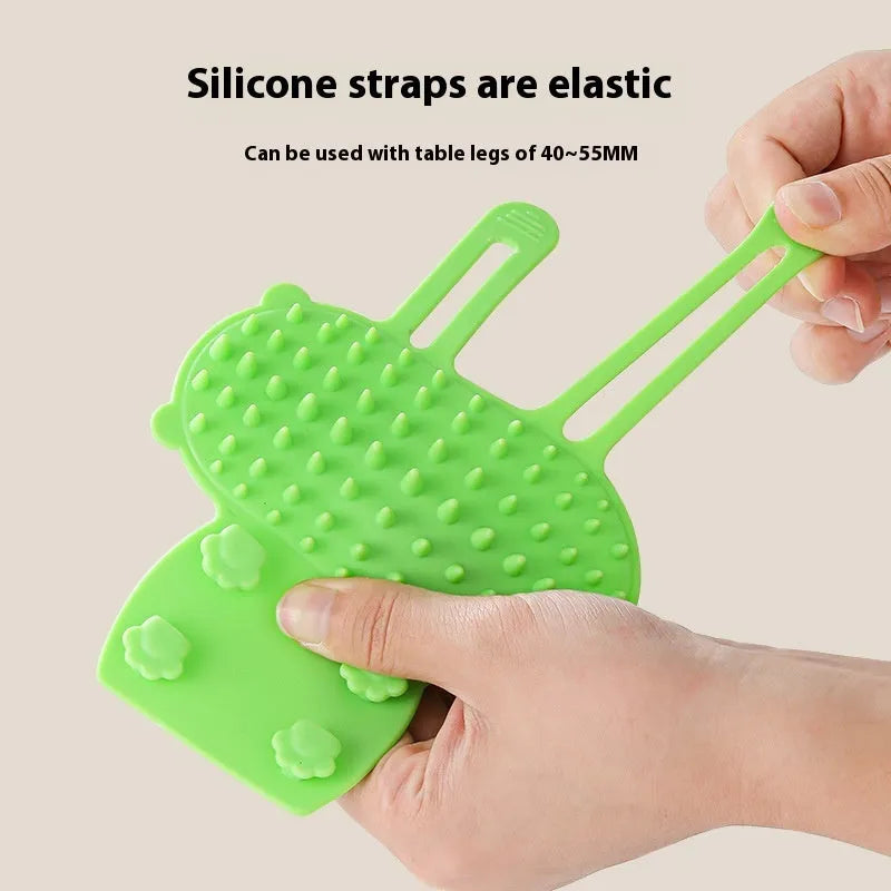 Silicone wall-mounted cat grooming brush with comb teeth and adjustable strap for table legs.