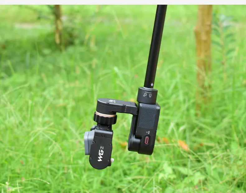 Black retractable selfie stick extended with phone in holder and visible wrist strap.