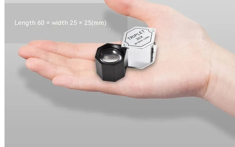 Handheld metal magnifying glass with optical glass lens for inspecting jewellery and coins.