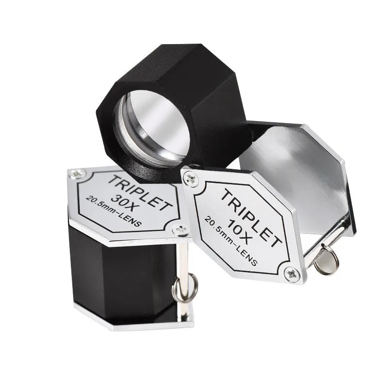 Handheld metal magnifying glass with optical glass lens for inspecting jewellery and coins.