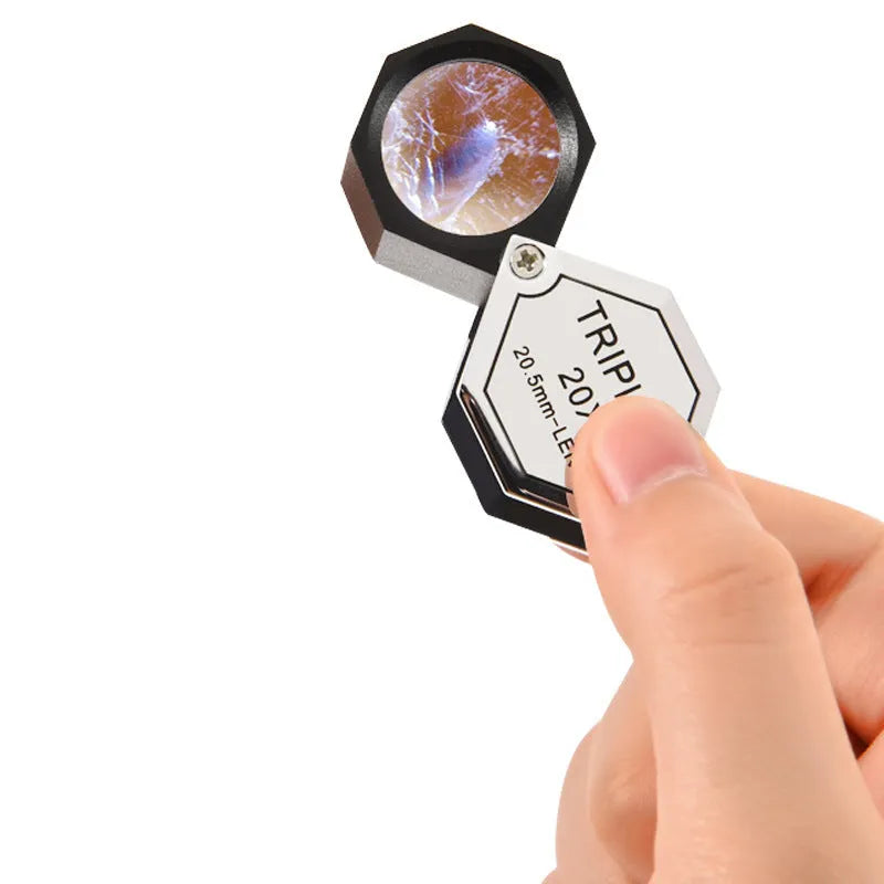 Handheld metal magnifying glass with optical glass lens for inspecting jewellery and coins.