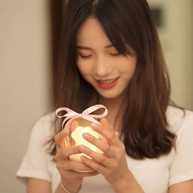 Grey and pink cat paw shaped USB rechargeable night light with adjustable brightness on a desk.