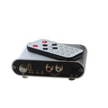 Silver aluminium audio source selector switch with infrared remote control on a shelf.
