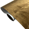 Roll of self-adhesive black leather suede fabric with adhesive backing visible, showing texture.