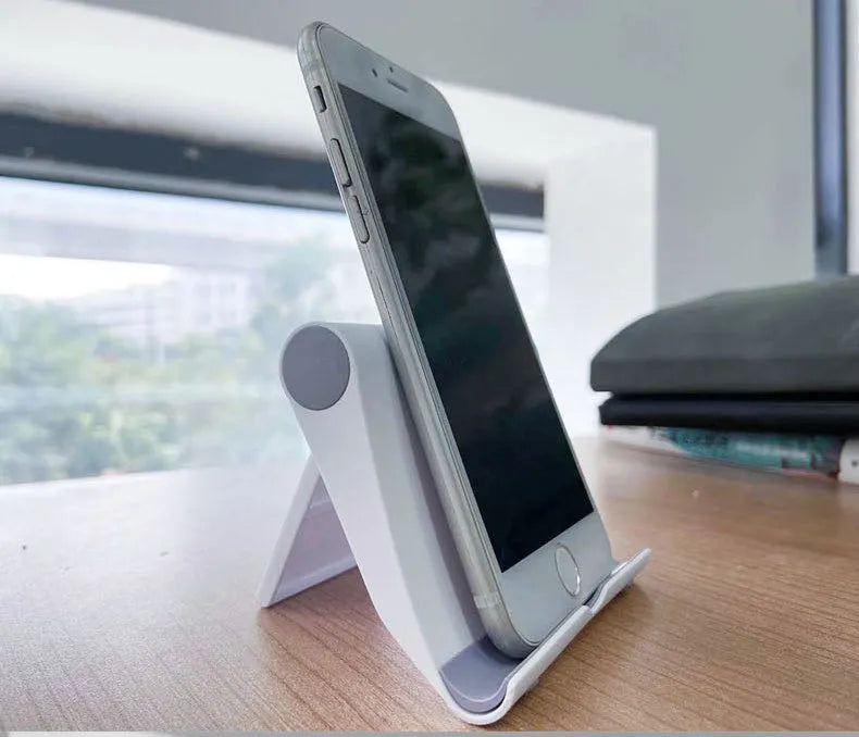Black PE folding mobile phone stand with soft rubber grips holding a tablet at an adjustable angle