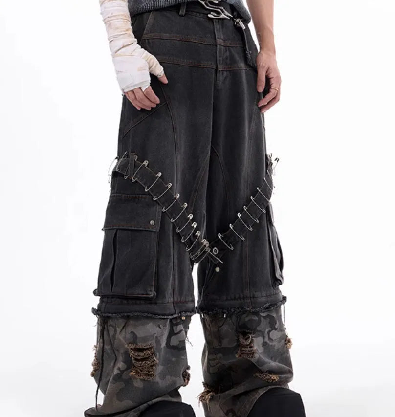 Men's grey camouflage pattern jeans with spliced panels and decorative pin details.