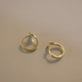 S925 sterling silver fishtail hoop earrings in gold colour on a white background.