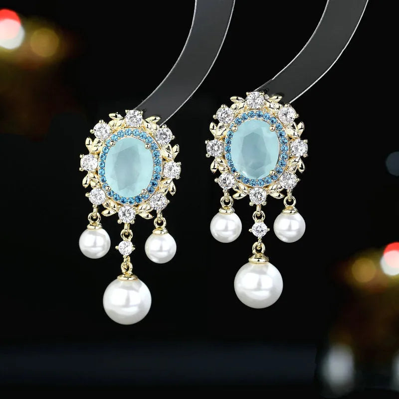 A pair of geometric ellipse-shaped drop earrings with a tassel, featuring pearls and inlaid zircon stones on copper.
