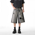 Grey women's denim shorts with distressed hole details and a loose, cropped fit