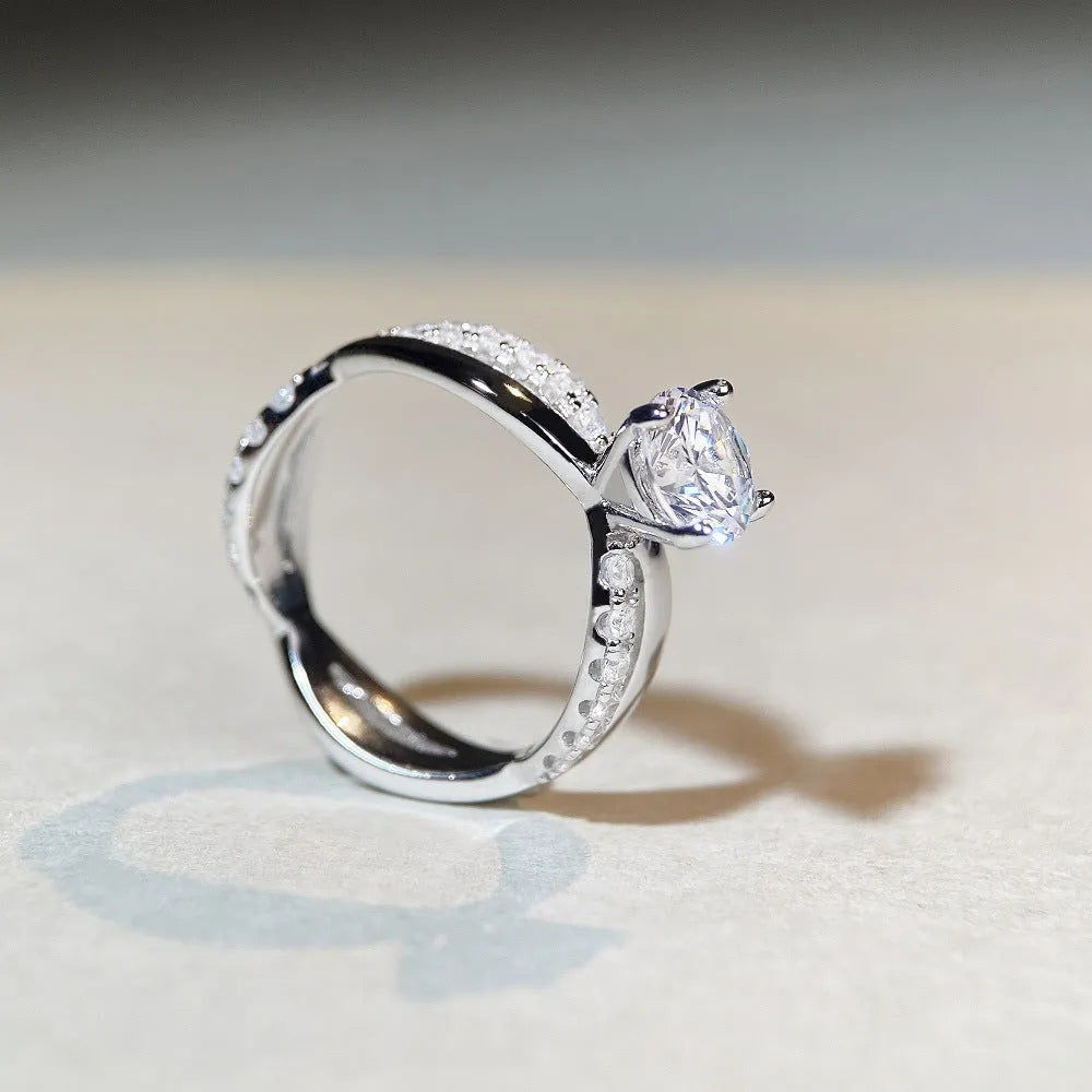 Silver geometric cross ring with a 1 carat moissanite in a four-claw twisted arm setting.